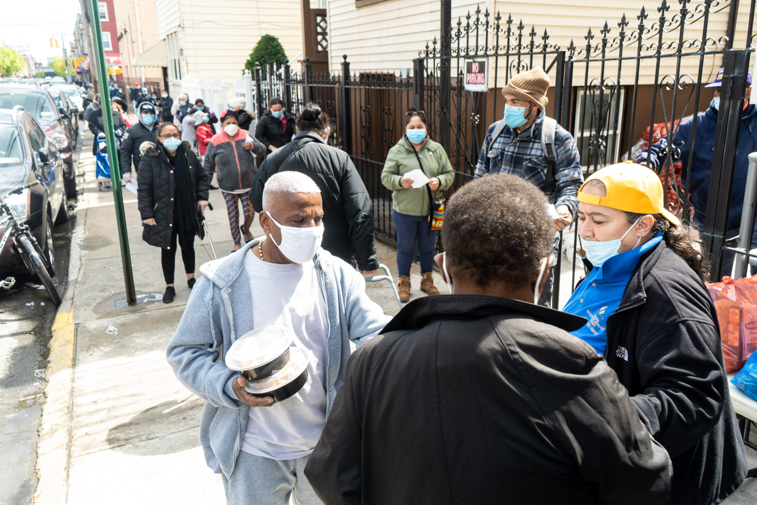 May 11, 2020: Food distribution outside the Corona Seventh-Day Adventist Church, 35-30 103rd Street, Corona, Queens, New York. A family of three receives food for three days, including a chicken, fruit, vegetables, cereal, and milk. © Camilo José Vergara
