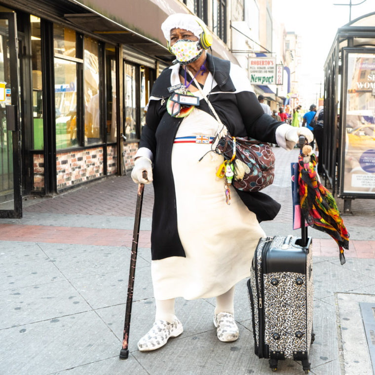 June 10, 2020: Sister Mary wearing two face masks and gloves on Broad Street at West Market Street in Newark, New Jersey. One of the pins on her lapel reads: “Jesus is coming soon.” © Camilo José Vergara 