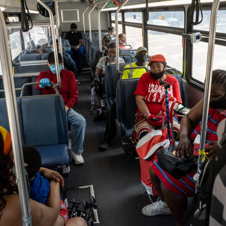 June 10, 2020: Bus traveling along Broad Street by Lincoln Park in Newark, New York. The woman’s red T-shirt reads: “Ambrose slapped me like a slave.” © Camilo José Vergara 