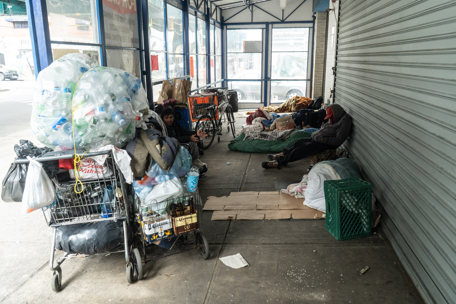 April 29, 2020: Homeless men and their shopping carts find shelter in a former discount store entryway, 78th Street at Roosevelt Avenue, Queens, New York. © Camilo José Vergara