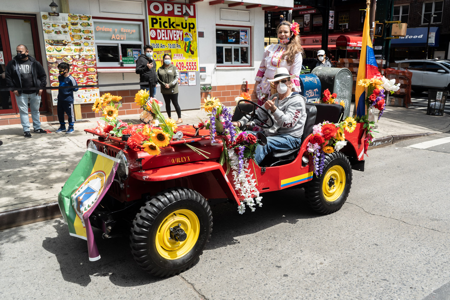 May 24, 2020: To advertise their restaurant over Memorial Day weekend, this couple celebrates their Colombian heritage in a decorated Jeep, 81-01 Roosevelt Avenue, Queens, New York. © Camilo José Vergara
