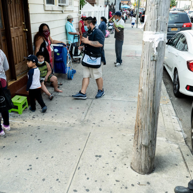 August 17, 2020: Families lining up to get free food, while a U.S. Census worker talks to a woman, her children by her side. Corona Seventh Day Adventist Church, 3530 103rd Street, Queens, New York. © Camilo José Vergara 