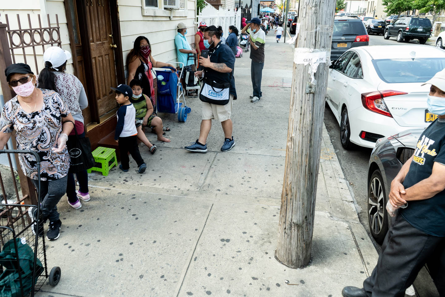 August 17, 2020: Families lining up to get free food, while a U.S. Census worker talks to a woman, her children by her side. Corona Seventh Day Adventist Church, 3530 103rd Street, Queens, New York. © Camilo José Vergara