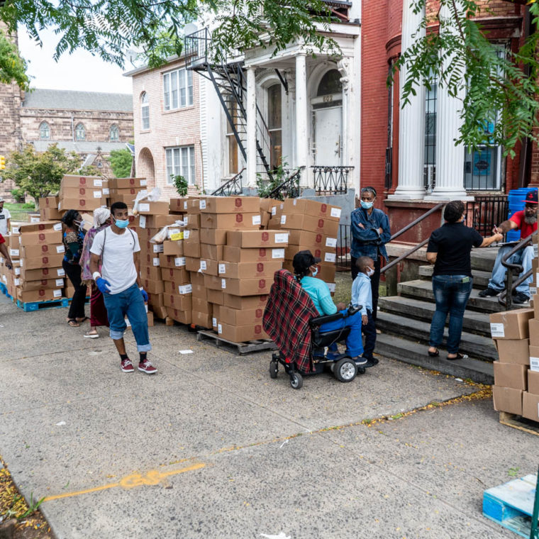 September 11, 2020: Kendall distributing donated boxes of bread to passersby. Saint James Social Services Corporation, 604 Dr. Martin Luther King Jr. Boulevard, Newark, New Jersey. © Camilo José Vergara 